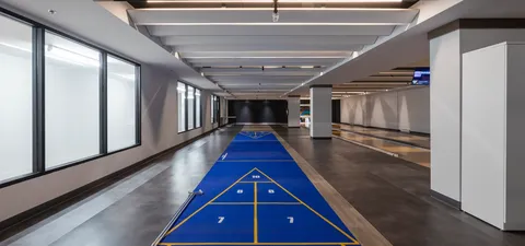 Indoor shuffleboard court beside large windows