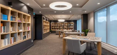 Library with bookshelves, tables and upholstered chairs