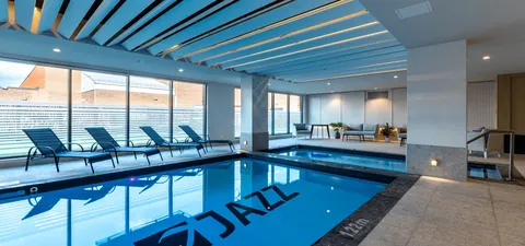 Indoor swimming pool with lounge chairs beside large windows