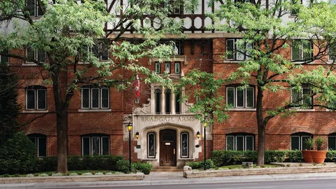 Brick residence entrance framed by mature trees and landscaping.