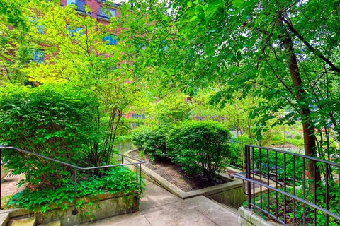 Garden path and railings among shrubs and mature trees.