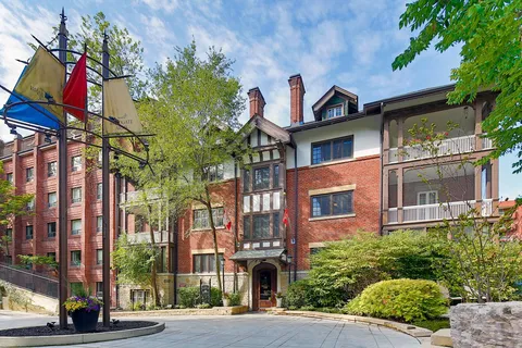 Street view of the brick residence, bay windows and flagpoles.
