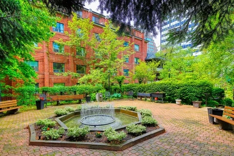 Brick courtyard with a central fountain, benches and garden beds.