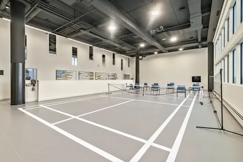 Indoor court with painted lines, a net and chairs along the wall