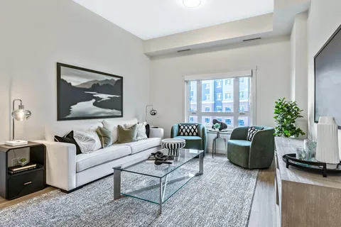 Sitting area with a pale sofa, green chairs and a glass coffee table