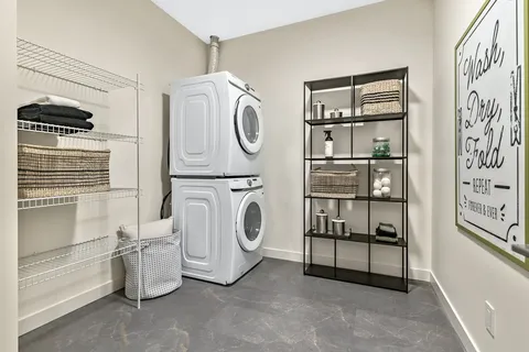 Laundry room with stacked washer and dryer, shelves and baskets