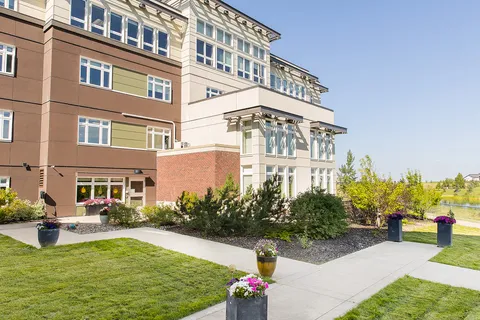 Residence exterior beside a lawn, paved path and flower pots.