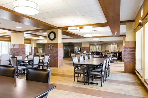 Dining room with dark tables and chairs beneath ceiling lights.