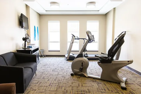 Fitness room with a treadmill, exercise bicycle and armchair.