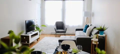 Sitting area with a sofa, armchair and television beside a dining table