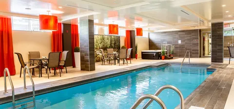 Indoor pool beside tables, chairs and red curtains