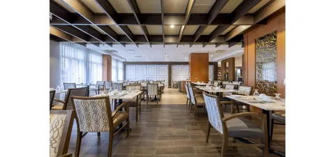 Dining room with set tables, patterned chairs and tall windows