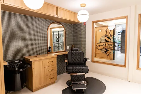 Barbershop with a black barber chair, mirror and wooden cabinets