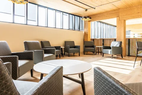 Armchairs and round tables in a bright room beside tall windows