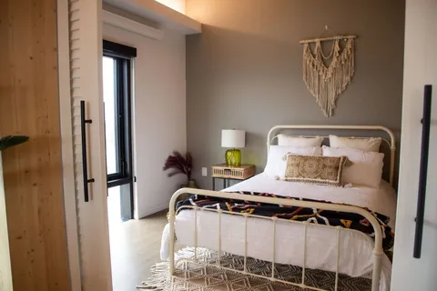 Bedroom with a white metal bed frame and woven wall hanging