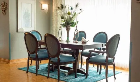 Long table and six blue chairs beside a bright window