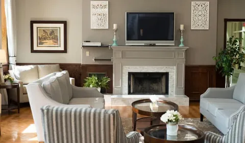 Armchairs and sofas around coffee tables facing a fireplace and television