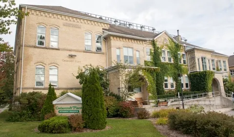 Historic brick building with arched windows, ivy and landscaped grounds