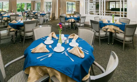Set dining tables with blue cloths beside tall windows