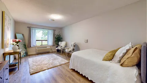 Bedroom with double bed, armchairs and large window