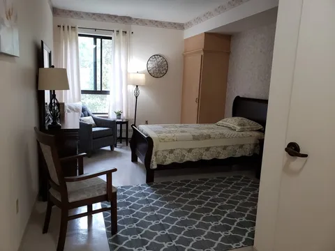 Bedroom with a bed, patterned rug and armchair by the window