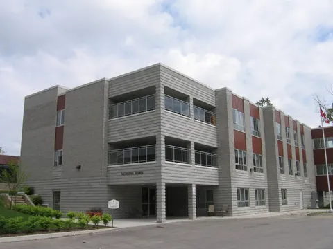 Three-storey residence with balconies beside an entrance driveway
