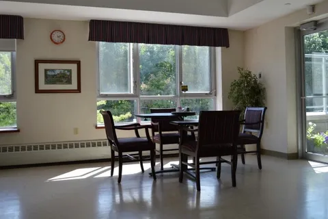 Dining table with chairs beside a large window