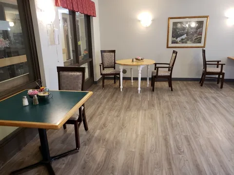 Tables and chairs beside windows and a framed landscape painting