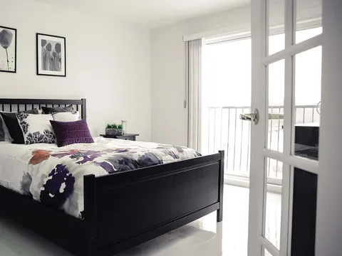 Bedroom with dark wooden furniture, floral bedding and glass-panelled doors