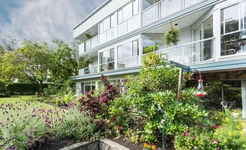 Residence facade with enclosed balconies above a landscaped garden.