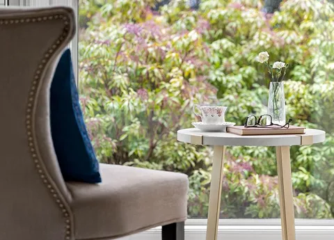Armchair and side table beside a window overlooking the garden.
