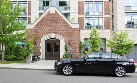 Residence facade and entrance with a car parked along the street.