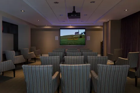 Theatre with striped armchairs facing a screen.