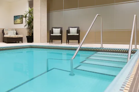 Indoor pool with entry rails and poolside seating.