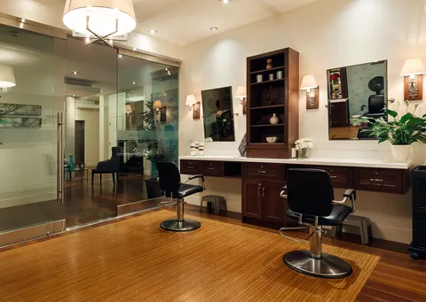 Salon with styling chairs, mirrors and wooden cabinets.