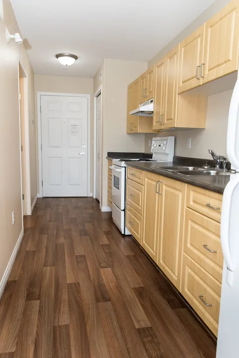 Kitchen with wooden cabinets, a stove, sink and refrigerator