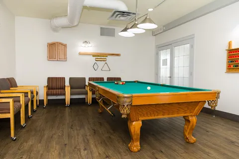 Games room with a pool table and wooden chairs