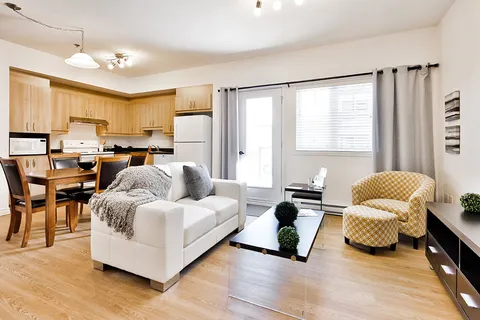 Open room with a kitchen, dining table, sofa and armchair