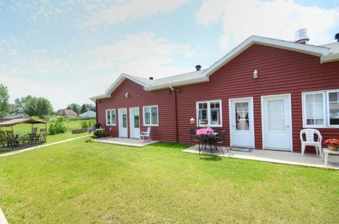 Red single-storey residence wings beside a lawn.