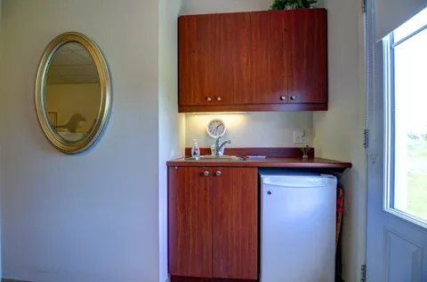 Suite kitchenette with wooden cabinets and a small refrigerator.