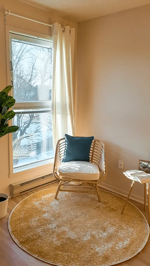 Wicker chair and a circular rug beside a tall window.