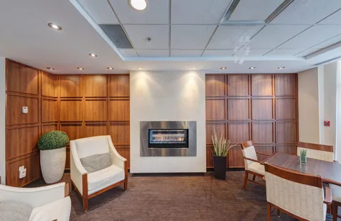 Armchairs and a side table beside a fireplace in a wood-panelled room