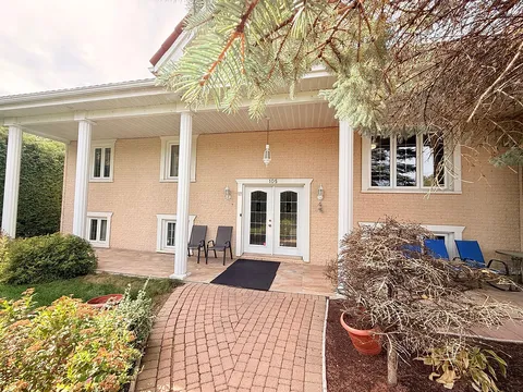 Covered entrance with white columns, glass doors, patio chairs and a brick path