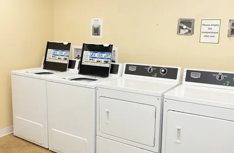 Laundry room with two white washing machines and two dryers