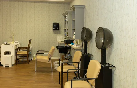 Salon with beige chairs, hooded hair dryers and a wash basin