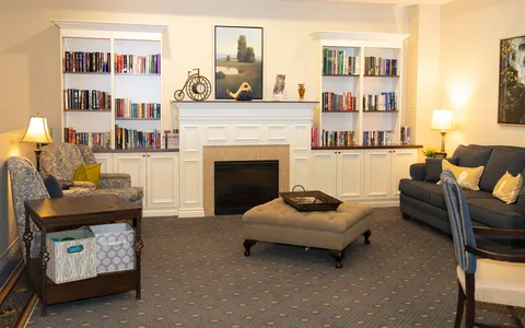 Library sitting area with bookshelves, a fireplace, armchairs and a sofa