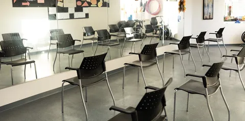 Room with rows of black chairs, a mirrored wall and exercise hoops