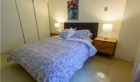 Bedroom with a double bed, wooden bedside cabinets, lamps and floral wall art