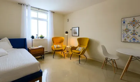 Bedroom with a single bed, two yellow armchairs and a small round table