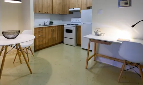 Kitchen with wooden cabinets, a white stove and fridge beside a table and desk